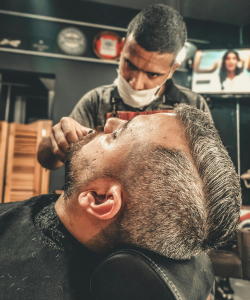 Barbeiro fazendo a barba de homem com cabelo cortado